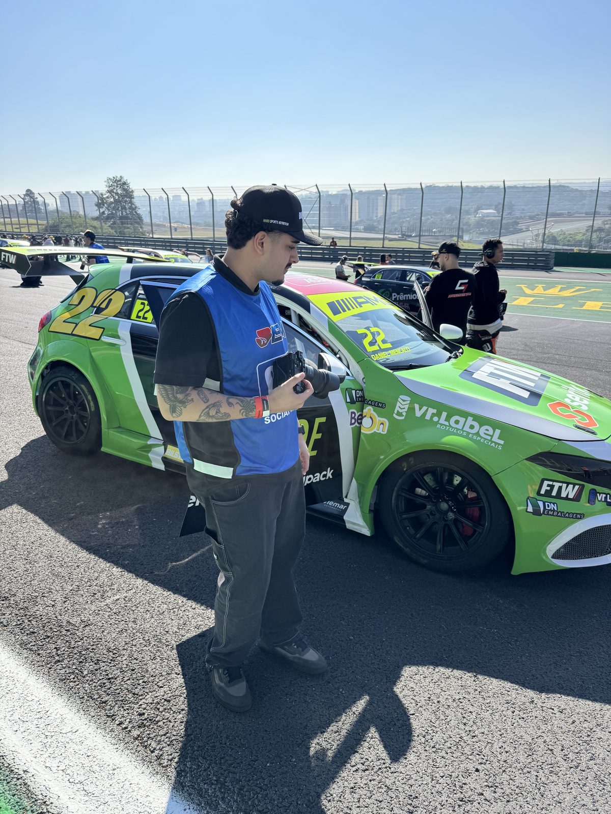 Filipe com a câmera no grid de largada de uma corrida de automobilismo